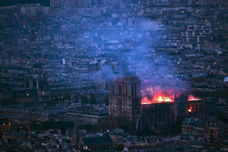 This general view taken from Montparnasse Tower shows flames and smoke as they billow from the roof at Notre-Dame Cathedral in Paris on April 15, 2019. - A fire broke out at the landmark Notre-Dame Cathedral in central Paris, potentially involving renovation works being carried out at the site, the fire service said.Images posted on social media showed flames and huge clouds of smoke billowing above the roof of the gothic cathedral, the most visited historic monument in Europe. (Photo by Philippe LOPEZ / AFP)