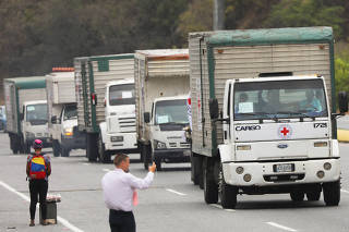 Trucks believed to be carrying humanitarian aid, drive on a highway outside Caracas