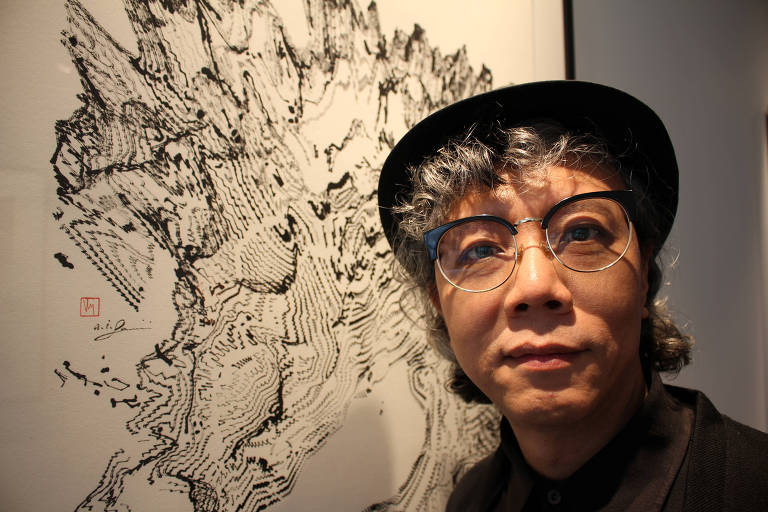 Artista Victor Wong posa em frente de uma das obras de sua exibição "Far Side of the Moon" 