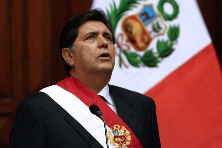 Alan Garcia, de terno, veste faixa presidencial nas cores da bandeira do Peru e canta hino de cabeça erguida; ao fundo, bandeira do Peru