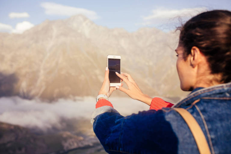 Mulher tira foto de montanhas com o celular