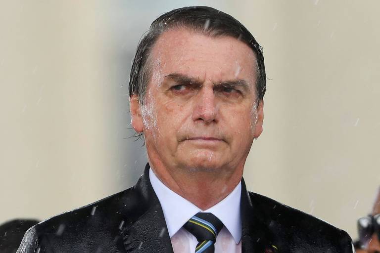 Sob chuva, o presidente Jair Bolsonaro participa de cerimônia em Brasília 