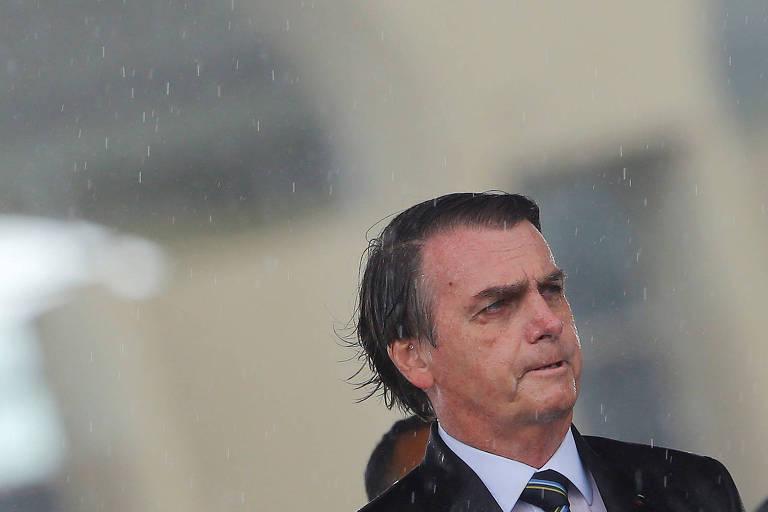 Sob chuva, o presidente Jair Bolsonaro participa de cerimônia em Brasília