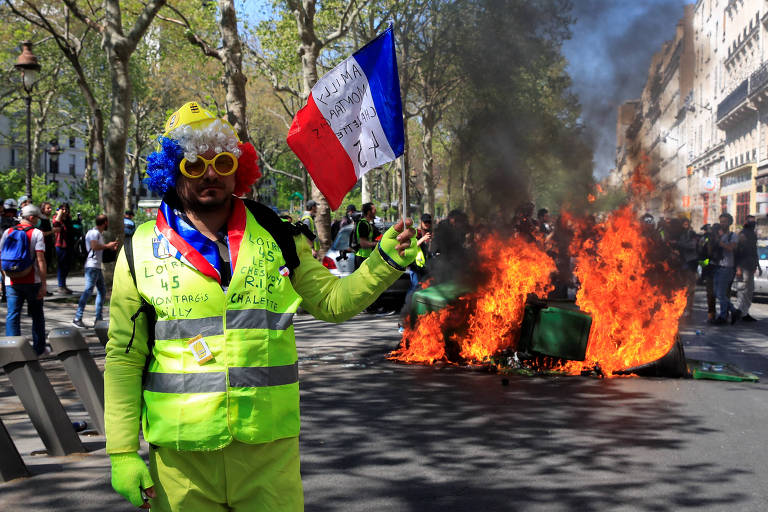 Um manifestante segura a bandeira francesa durante protesto de coletes amarelos 
