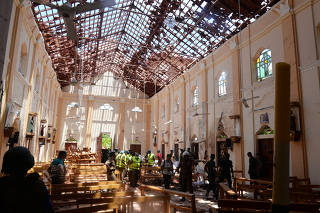 Crime scene officials inspect the site of a bomb blast inside a church in Negombo
