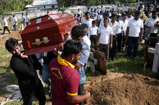A coffin of a victim is carried during a mass burial of victims at a cemetery near St. Sebastian Church in Negombo