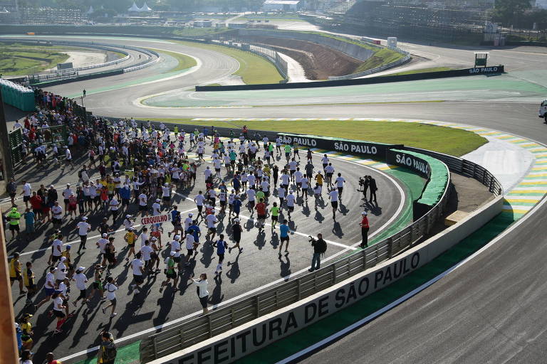 Imagem aérea mostra maratonistas correndo em uma pista de corrida de fórmula 1