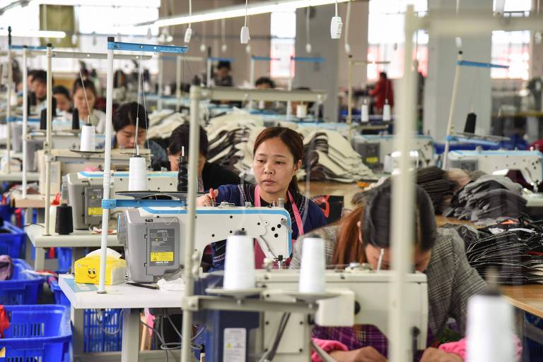 Operárias chinesas trabalham em máquinas de costura em fábrica 