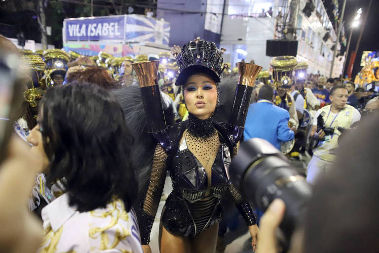 Sabrina Sato desfilando na Unidos da Vila Isabel no Carnaval 2019. Ela está de roupa preta, mandando beijos. 