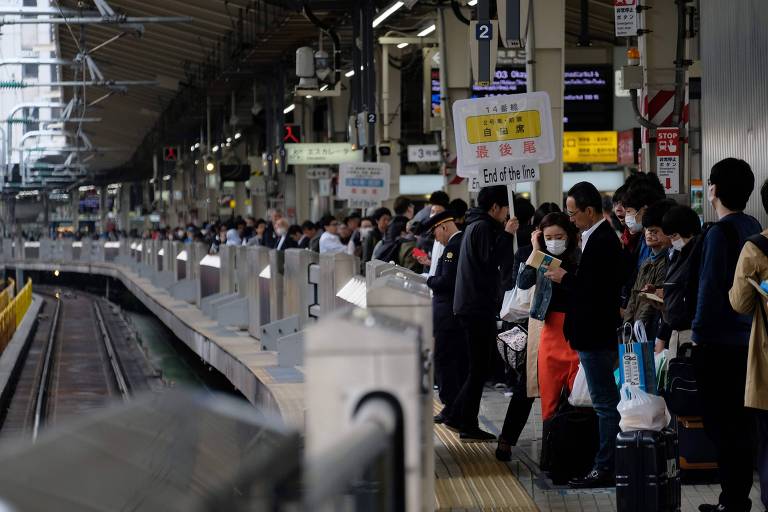 Passageiros esperam por trem na estação ferroviária de Tóquio neste sábado (27)