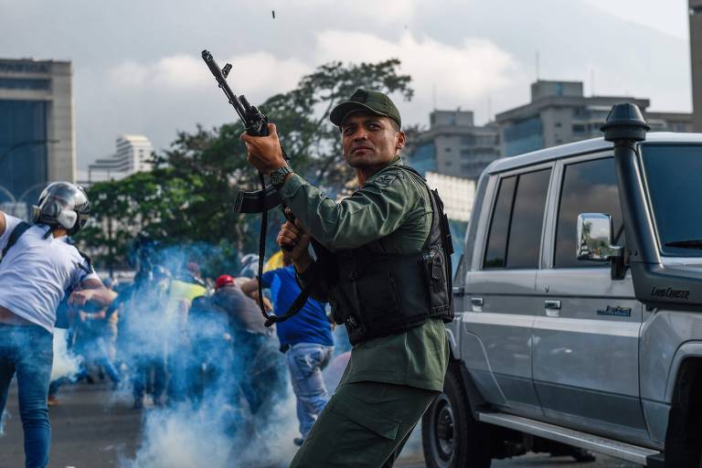 Em Caracas, membro da Guarda Nacional Bolivariana que passou a apoiar o oposicionista Juan Guaidó atira para o alto para repelir as forças leais a Maduro
