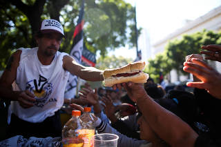 A man gives a sausage sandwich to a demonstrator during a May Day protest against Argentina's President Mauricio Macri's policy, in Buenos Aires