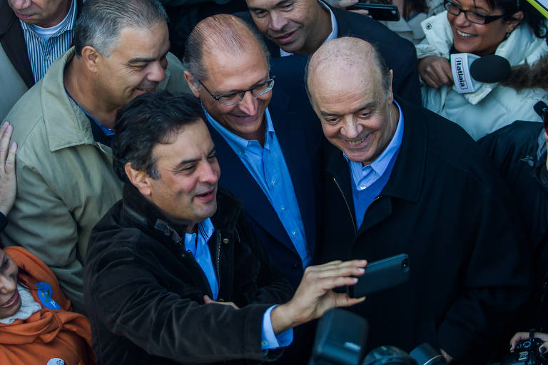 O então candidato à Presidência pelo PSDB, Aécio Neves (Esq.), acompanhado do governador do estado de São Paulo e candidato a reeleição Geraldo Alckmin (Centro), e do candidato ao Senado José Serra (Dir.), tiram selfie durante campanha eleitoral em frente a fábrica no Jaraguá, em São Paulo (SP)