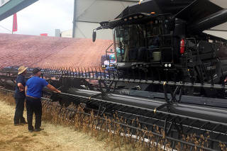 Farmers look at a large grain harvester during the Agrishow farm equipment fair in Ribeirao Preto