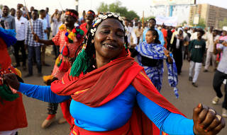 Sudanese protesters dance during a demonstration in front of the defense ministry compound in Khartoum