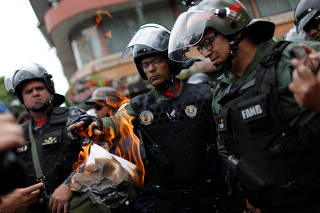 A member of the national guard burns a document that was delivered by a citizen near a military base in Caracas