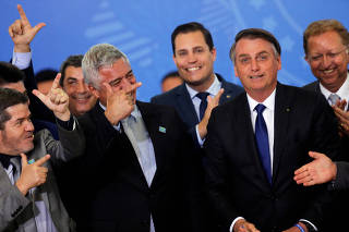 Congressmen react near the Brazil's President Jair Bolsonaro during a ceremony for signature of the decree of the new regulation on the use, sale and carrying of weapons and ammunition, at Planalto Palace in Brasilia