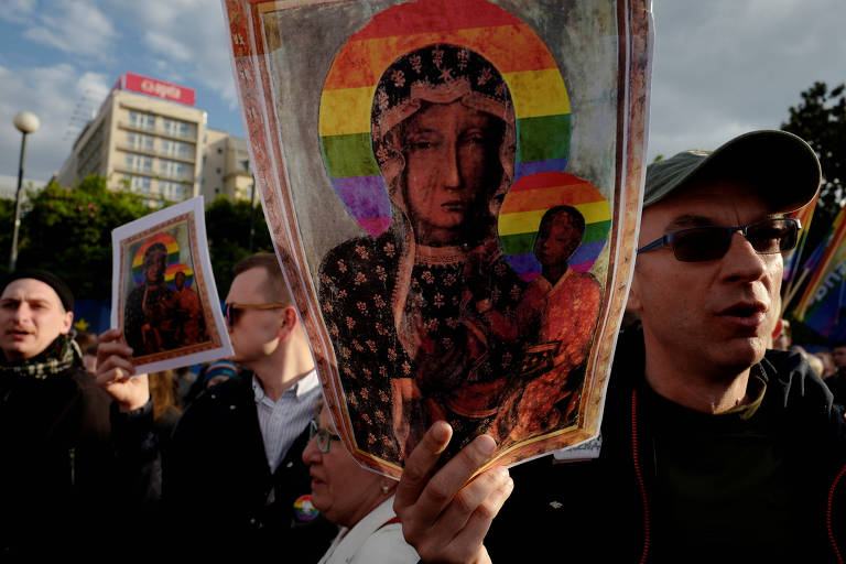 Manifestantes levam cartazes com a imagem da Virgem Negra de Czestochowa com a coroa de arco-íris inserida pela artista Elzbieta Podlesna em protesto nesta terça (7)
