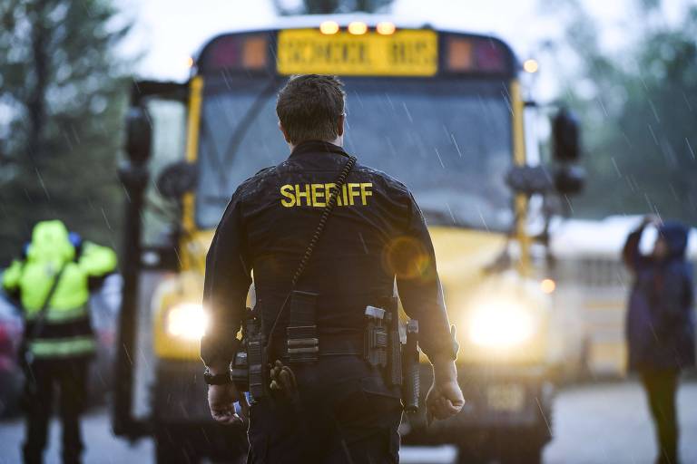 Um agente da delegacia do xerife local acompanha retirada de alunos da escola Stem, ao sul de Denver