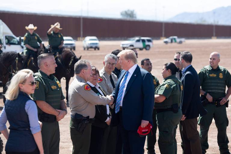 O presidente dos EUA, Donald Trump, conversa com membros da alfândega enquanto percorre o muro na fronteira com o México, na Califórnia