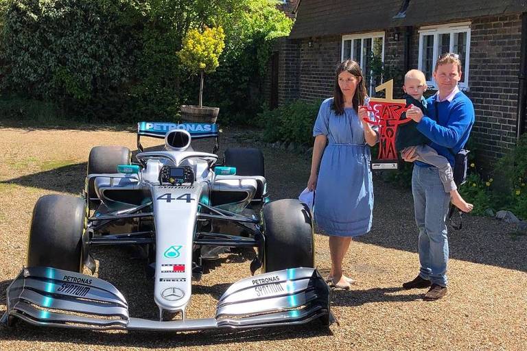 Harry Shaw com os pais diante de carro da Fórmula 1 deixado na frente da casa da família