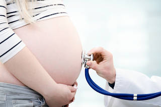 Doctor using stethoscope examining pregnant woman