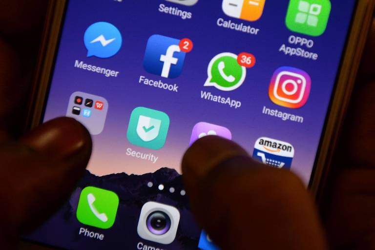 dois dedos mexem em tela de celular com ícones apps de redes sociais, como facebook, instagram, whatsapp, etc