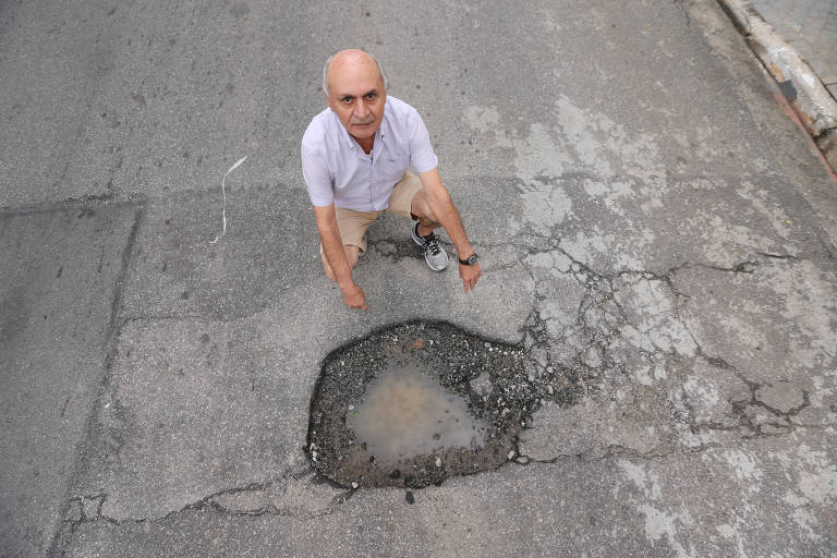 O aposentado Francisco Nogueira de Souza mostra o buraco que está aberto em frente à sua casa