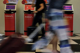 Customers walk past Avianca airline check-in machines at Congonhas airport in Sao Paulo