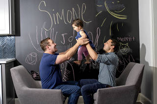 James Derek Mize, left, and his husband, Jonathan Gregg, with their infant daughter Simone, who was born in England to a surrogate mother, in Decatur, Ga.