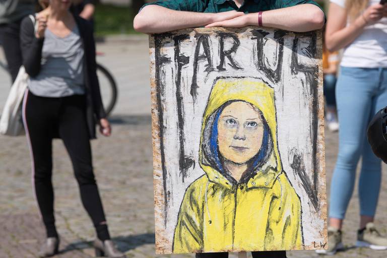 Participante de ato segura cartaz com o desenho de Greta Thunberg e a frase "Fear Us" (Tenham medo de nós)