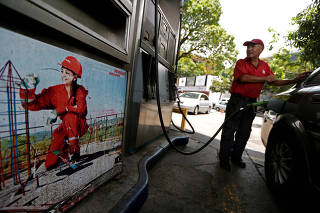 A worker pumps fuel into a vehicle at a state oil company PDVSA's gas station in Caracas