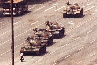 FILE PHOTO: A man stands in front of a convoy of tanks in the Avenue of Eternal Peace in Beijing