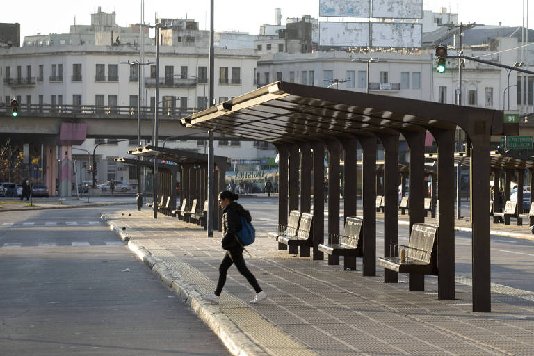 Mulher caminha por ponto de ônibus em terminal vazio de Buenos Aires