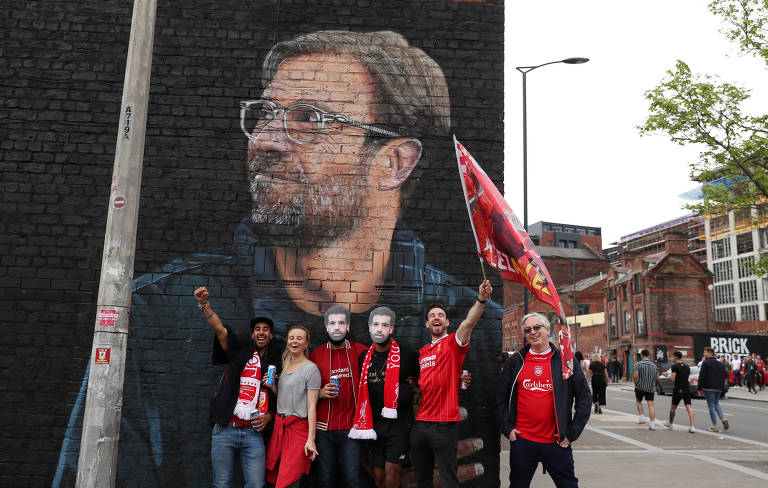 Torcedores do Liverpool com máscaras do jogador Mohamad Salah em frente a mural com a foto do técnico Juergen Klopp, antes da decisão da Champions League