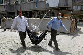 Afghan medical workers carry a dead body of a victim at the site of a suicide bomb attack in Kabul