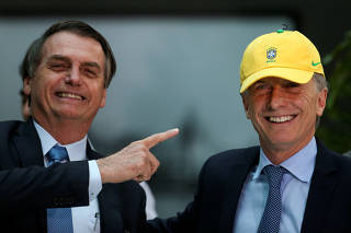 Brazil's President Jair Bolsonaro points at Argentina's President Mauricio Macri who poses with Brazil's soccer team's cap, next to at the Casa Rosada government house in Buenos Aires