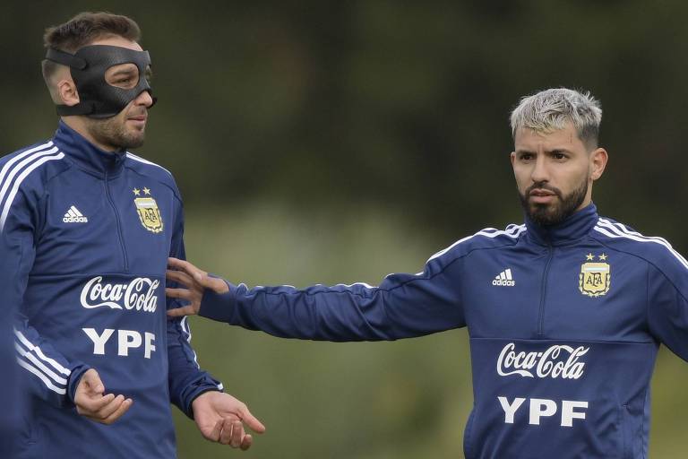 À esquerda, o zagueiro mascarado Germán Pezzella, ao lado do atacante Sergio Aguero