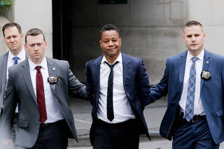 Actor Cuba Gooding Jr. is escorted handcuffed by NYPD officers as he exits the New York City Police Department's (NYPD) Special Victims Division (SVU) in the Harlem neighbourhood of New York