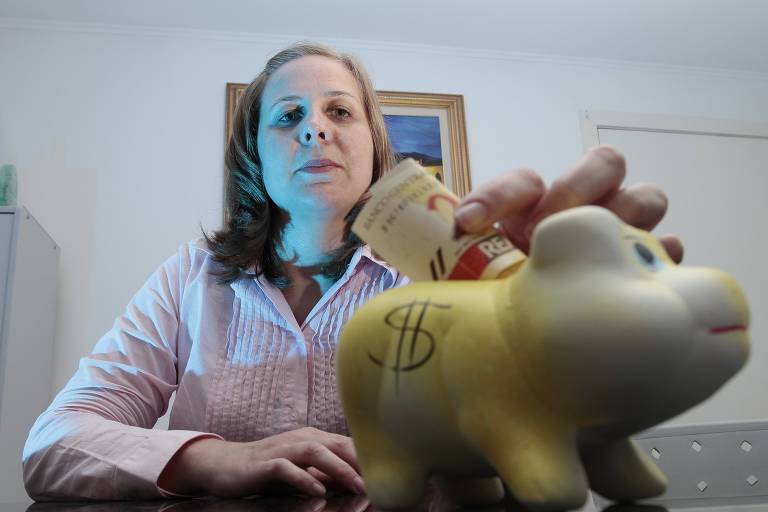 Mulher coloca nota de R$ 20 no cofrinho de porco