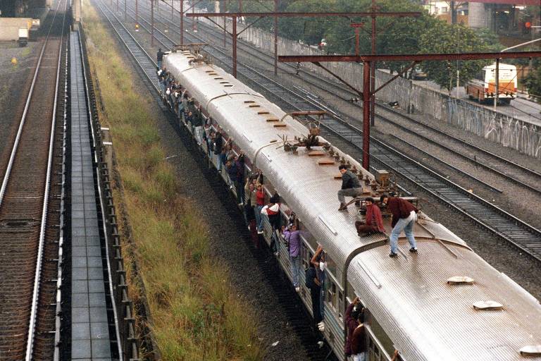 Passageiros 'surfam' sobre trem, lotado devido à greve do metrô em 1995, em São Paulo (SP)