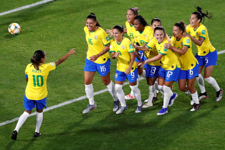 Marta aponta para grupo de jogadoras que corre na sua direção em comemoração de gol