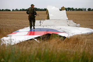 FILE PHOTO: Armed pro-Russian separatist stands on part of the wreckage of the Malaysia Airlines Boeing 777 plane after it crashed near the settlement of Grabovo in the Donetsk region