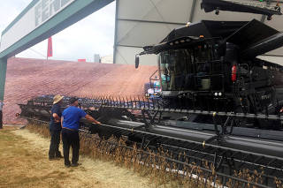 FILE PHOTO: Farmers look at a large grain harvester during the Agrishow farm equipment fair in Ribeirao Preto