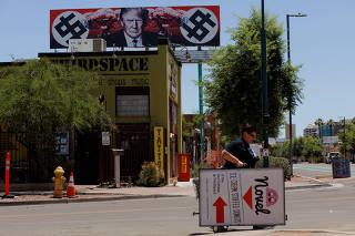 A billboard featuring U.S. President Trump hangs over a neighborhood in Phoenix