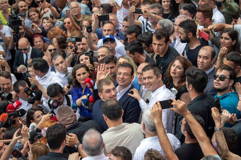 O candidato da oposição à prefeitura de Istambul, Ekrem Imamoglu (no centro, de óculos) acena após deixar colégio eleitoral 