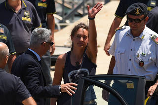 Carola Rackete, the 31-year-old Sea-Watch 3 captain, disembarks from a Finance police boat and is escorted to a car, in Porto Empedocle