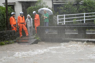 Rescue workers and local residents watch Wada river swollen due to heavy rain in Kagoshima