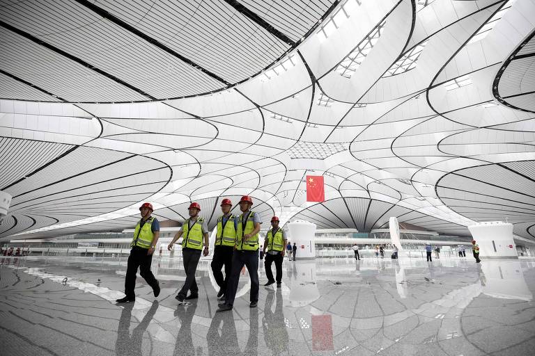 Trabalhadores atravessam o hall central de Daxing, que tem a meta de chegar a 100 milhões de passageiros transportados em 2040