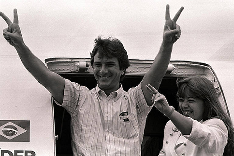 O candidato a presidente, Fernando Collor de Mello, faz gesto para público, ao lado de sua mulher Rosane em dezembro de 1989